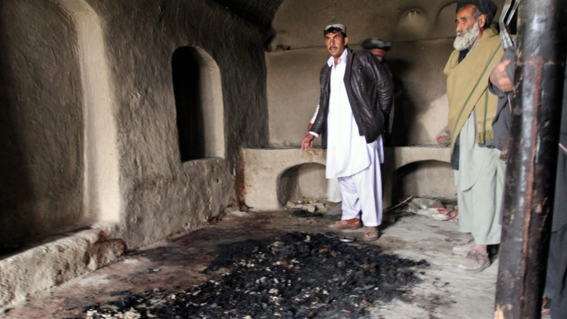 FILE - In this Sunday, March 11, 2012 file photo, men stand next to blood stains and charred remains inside a home where witnesses say Afghans were killed by a U.S. soldier in Panjwai, Kandahar province south of Kabul, Afghanistan. U.S. military officials began investigating the massacre site more than three weeks after the killings occurred. (AP Photo/Allauddin Khan, File)