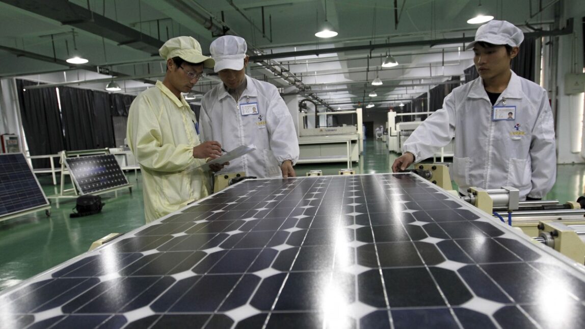 In this photo taken Wednesday March 21, 2012, workers examine solar panels at a manufacturer of photovoltaic products. (AP Photo)