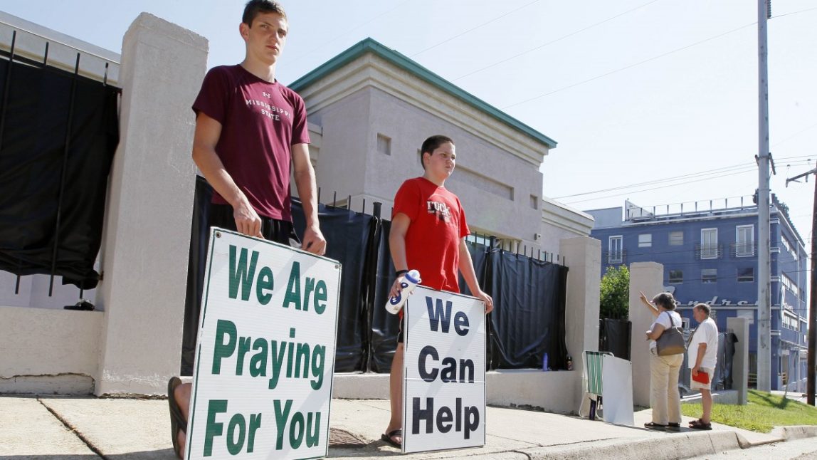 In this June 27, 2012 photograph, anti-abortion advocates stand outside Mississippi's only abortion clinic, singing and praying for their patients, and "counseling" them to reject abortion. (AP Photo/Rogelio V. Solis)
