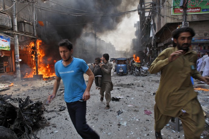 Pakistani run away from the site of a blast shortly after a car explosion in Peshawar, Pakistan, Sunday, Sept. 29, 2013. A car bomb exploded on a crowded street in northwestern Pakistan Sunday, killing scores of people in the third blast to hit the troubled city of Peshawar in a week, officials said. (AP Photo/Mohammad Sajjad)
