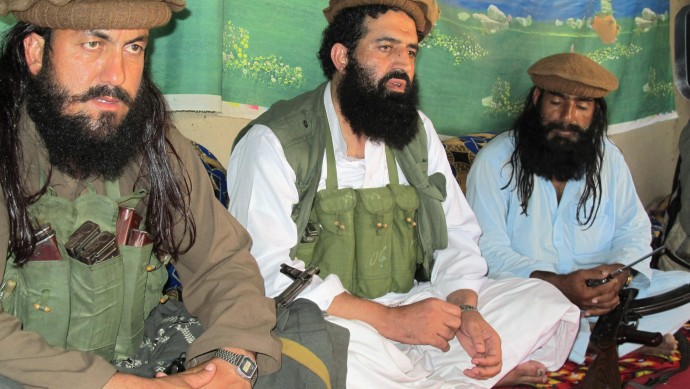 In this Saturday, Oct. 5, 2013 photo, Pakistani Taliban spokesman Shahidullah Shahid, center, flanked by his bodyguards, talks to reporters at an undisclosed location in Pakistani tribal area of Waziristan along Afghanistan border. The Afghan Taliban are financially supporting Pakistani militants at war with Islamabad and providing sanctuary for them in neighboring Afghanistan, the Pakistani Taliban's spokesman said, highlighting the risk both groups pose to the Pakistani government. (AP Photo/Ishtiaq Mahsud)