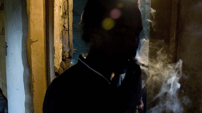 In this photo taken on Oct. 21, 2010, an unidentified man smokes a concoction called "whoonga" in the Kwadebeka Township near Durban, South Africa. AIDS patients in South Africa are being robbed of their lifesaving drugs so that these can be mixed with marijuana and smoked, authorities and health experts say. (AP Photo/John Robinson)