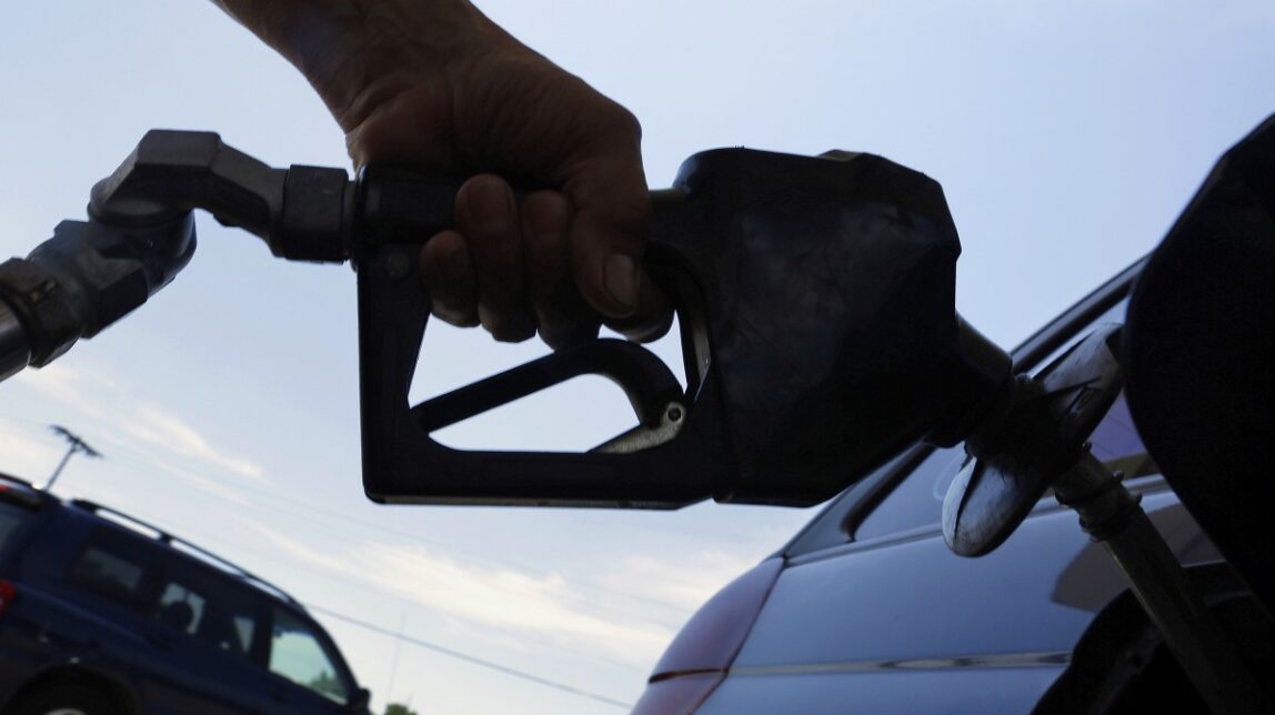 a motorist puts fuel in his car's gas tank at a service station