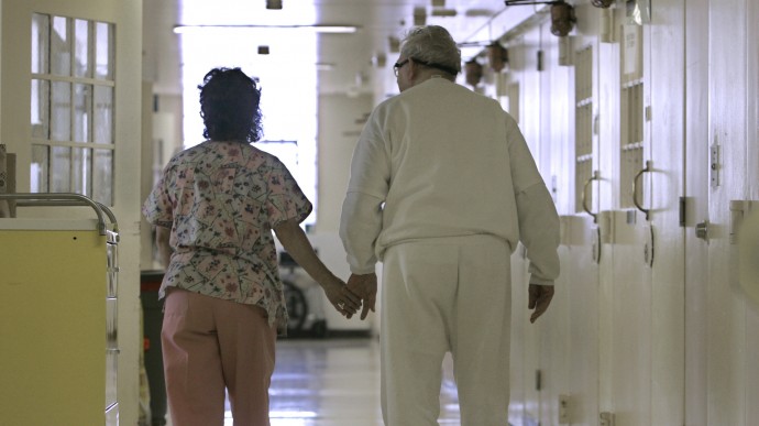 Debbie Coluter, a certified nurses assistant, assists an elderly inmate, with Alzheimers Disease, to his cell at the California Medical Facility in Vacaville, Calif., Wednesday,  April 9, 2008.  Older and terminally ill inmates cost two-to-three times as much to incarcerate as younger prisoners,  straining state prisons and costing  taxpayers billions of dollars. (AP Photo/Rich Pedroncelli)