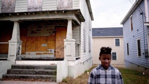 A boarded up home sits in the Mechanicsville neighborhood surrounding the Atlanta Braves stadium as a child plays out front, Wednesday, Nov. 20, 2013, in Atlanta. (AP Photo/David Goldman)