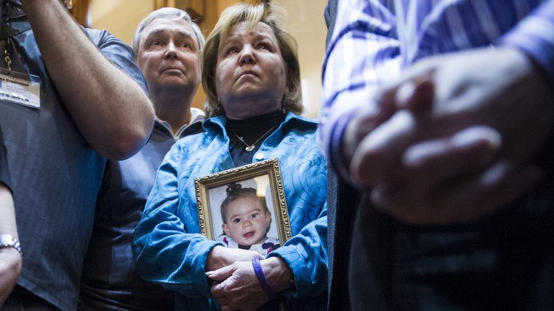 Medical marijuana advocate Barbara Kutchback, of Monroe, Ga., holds a photo of her three year old granddughter as she listens to other advocates tell of their children's suffering, after a bill to legalize marijuana for medicinal purposes was introduced in the State House chamber on Tuesday, Jan. 28, 2014, in Atlanta. Kutchback's granddaughter suffers from a rare epilepsy disease and they believe marijuana can help relieve her suffering.(AP Photo/John Amis)