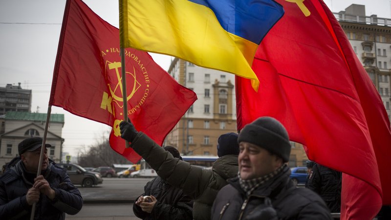 Russian Communist Party supporters hold Ukrainian national and red flags during a protest in front of the U.S. Embassy in Moscow, Russia, Friday, Feb. 7, 2014. U.S. officials say they suspect Russia is behind the leak of an apparently bugged phone conversation about Ukraine between two senior American diplomats in which they make disparaging comments about the European Union. (AP Photo/Alexander Zemlianichenko)