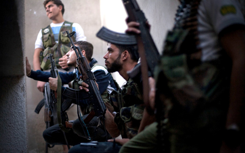 FSA fighters take cover from incoming Syrian Army fire in the Izaa district in Aleppo, Syria, Wednesday, Sept. 12, 2012. (AP/Manu Brabo)
