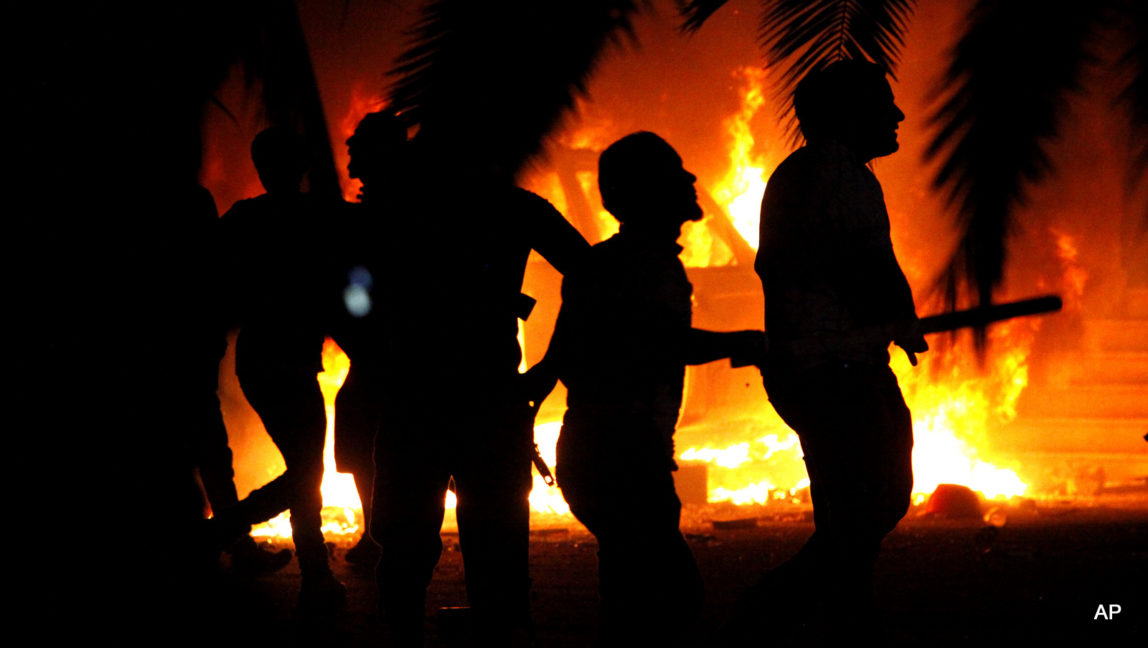 Libyan civilians watch fires at an Ansar al-Shariah Brigades compound, after hundreds of Libyans, Libyan Military, and Police raided the Brigades base, in Benghazi, Libya.