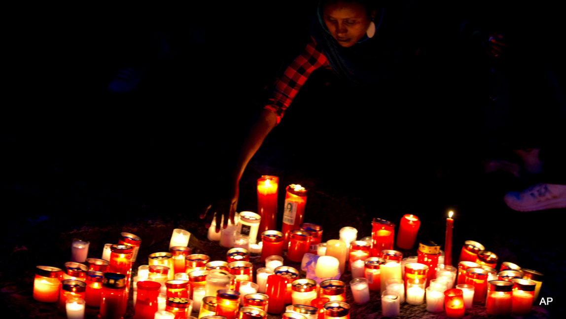 A woman lays a candle by the sea during a candle light vigil in Sliema, in the outskirts of Valletta, Malta, Wednesday, April 22, 2015. A smuggler's boat crammed with hundreds of people overturned off the coast of Libya on Saturday as rescuers approached, causing what could be the Mediterranean's deadliest known migrant tragedy. The burial ceremony of the 24 rescued bodies will take place in Malta Thursday.