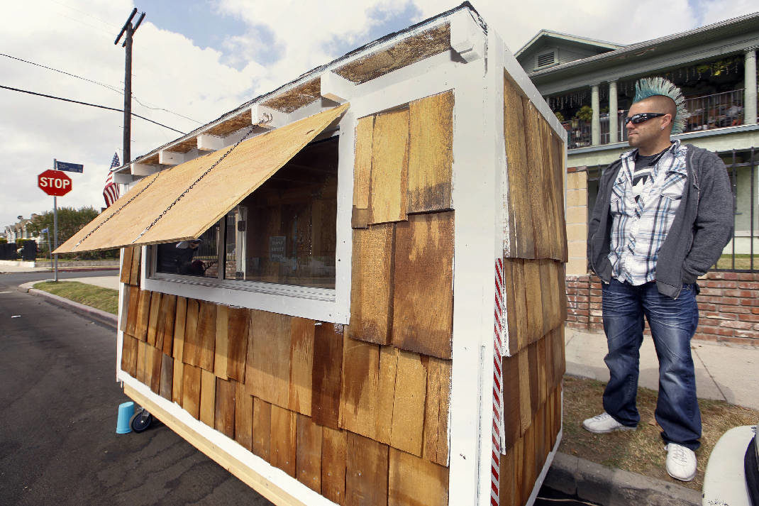 Los Angeles resident Elvis Summers poses with his tiny house on wheels he built for a woman who had been sleeping on the streets in his South Los Angeles neighborhood on Thursday, May 7, 2015. Summers never thought more than 5.6 million people would watch a YouTube video of him constructing the 8-foot-long house for Irene "Smokie" McGhee, 60, a grandmother who’s been homeless for more than a decade. He estimates he spent less than $500 on plywood, shingles, a window and a door.