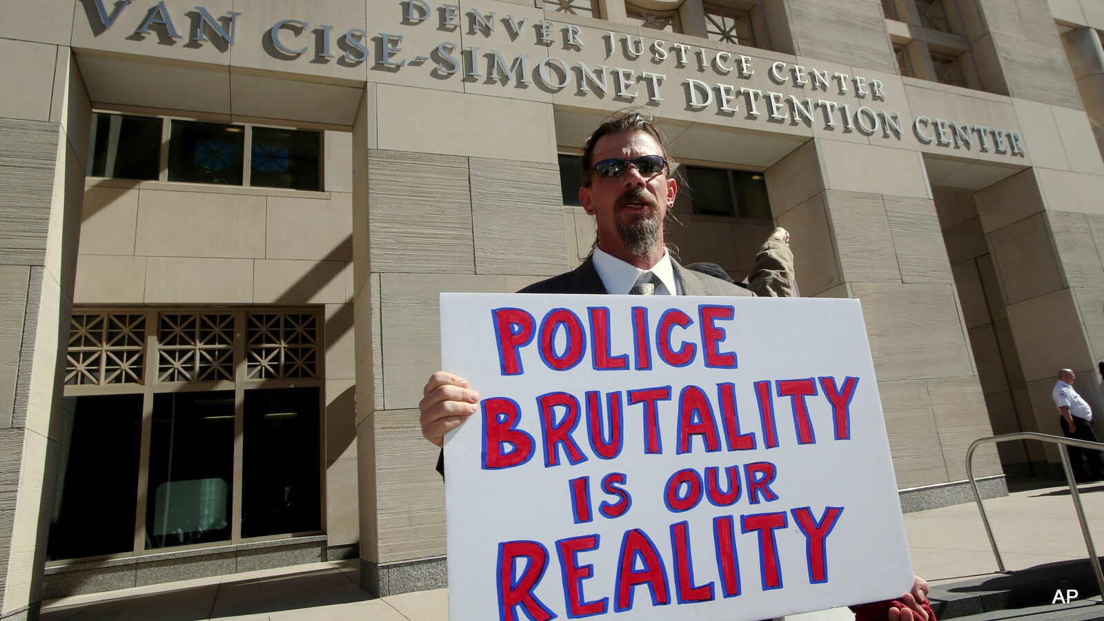 A protester Michael J. Moore holds a sign against the city jail in Denver, CO.