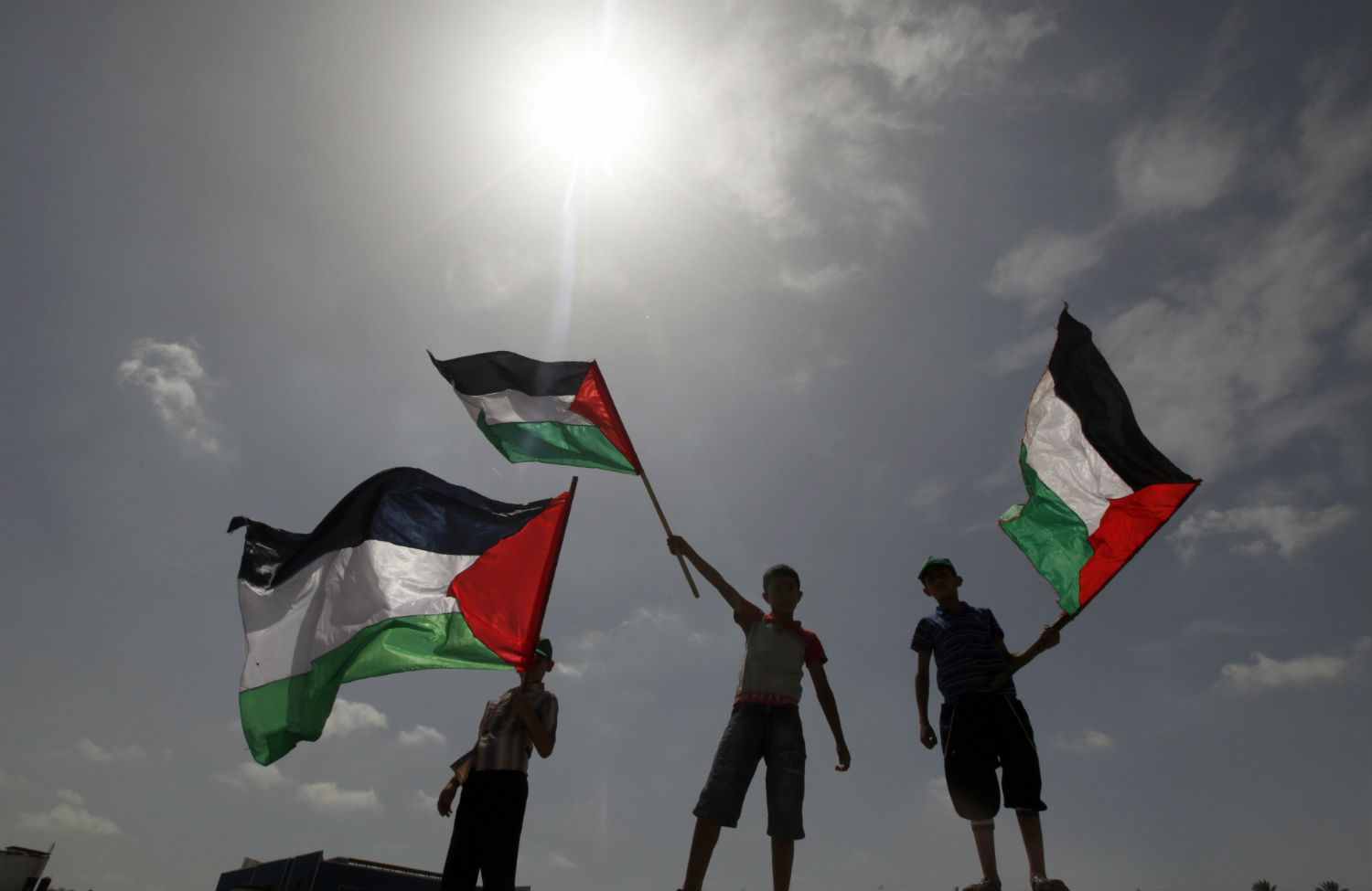 Palestinian boys wave national flags near the Erez border crossing between Gaza and Israel. (AP Photo/Hatem Moussa, File)