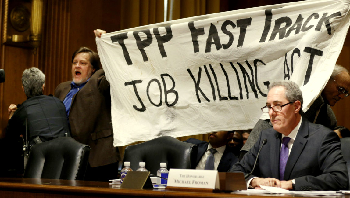 A policewoman removes activist Kevin Zeese for protesting the Trans-Pacific Partnership (TPP) as U.S. Trade Representative Michael Froman (R) testifies before a Senate Finance Committee hearing on "President Obama's 2015 Trade Policy Agenda" on Capitol Hill in Washington January 27, 2015. The top U.S. trade official urged Congress to back the administration's trade agenda on Tuesday and said an ambitious Pacific trade pact is nearing completion. Froman said the administration looked to lawmakers to pass bipartisan legislation allowing a streamlined approval process for trade deals, such as the 12-nation Trans-Pacific Partnership. REUTERS/Kevin Lamarque