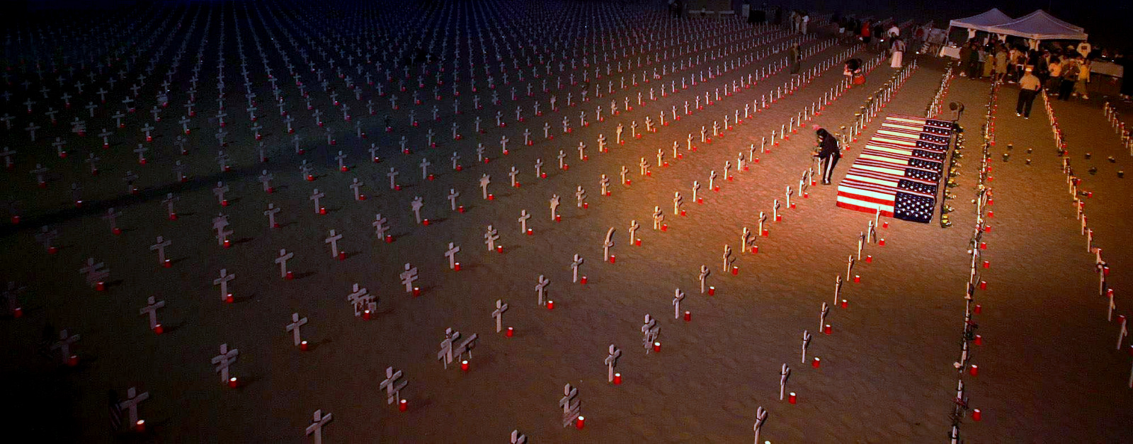 A volunteer puts flowers next to a cross at the Arlington West Iraq war memorial display on the beach next to the Santa Monica Pier in Santa Monica, Calif., on Saturday May 27, 2006. (AP Photo/Stefano Paltera)
