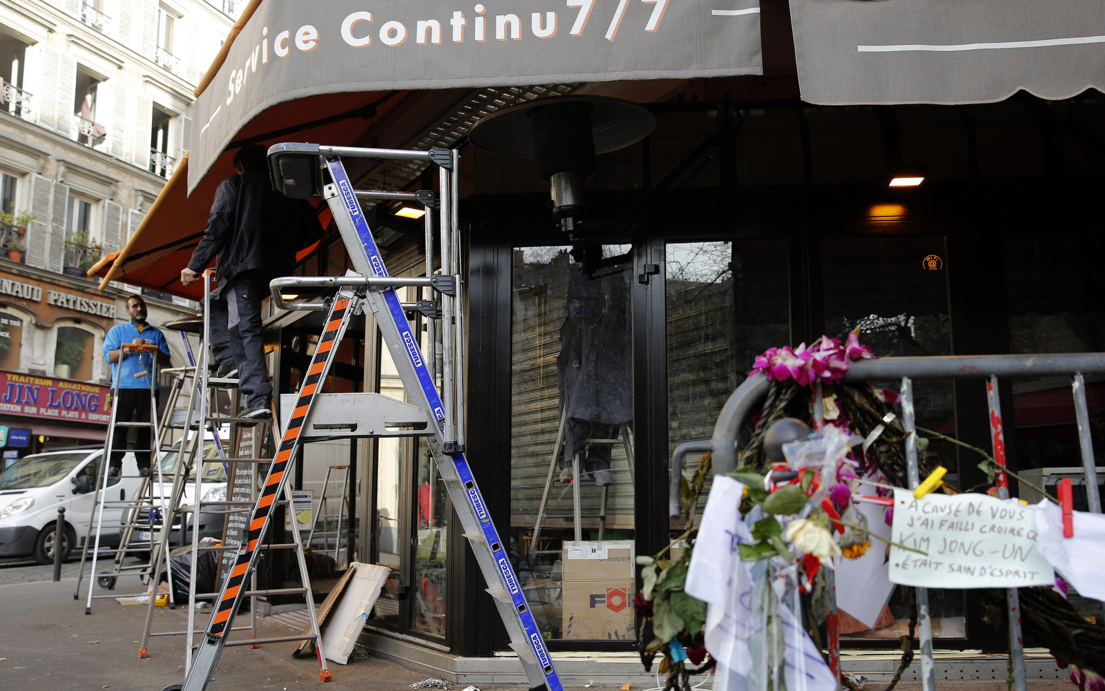 Men work on the shop front of the cafe "La bonne biere", one of the establishments targeted during the November Paris attacks, in Paris, Thursday, Dec. 3, 2015 . The cafe is expected to reopen Friday, Dec. 4. (AP Photo/Christophe Ena)