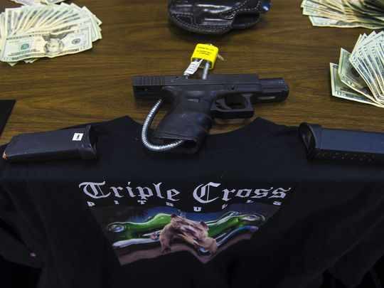 A gun, bills and a shirt displaying a Triple Cross Pitbulls logo were among the items seized by police and displayed during the press conference on Jan. 4, 2016 in Penn Township. (Photo: Clare Becker, The Evening Sun)