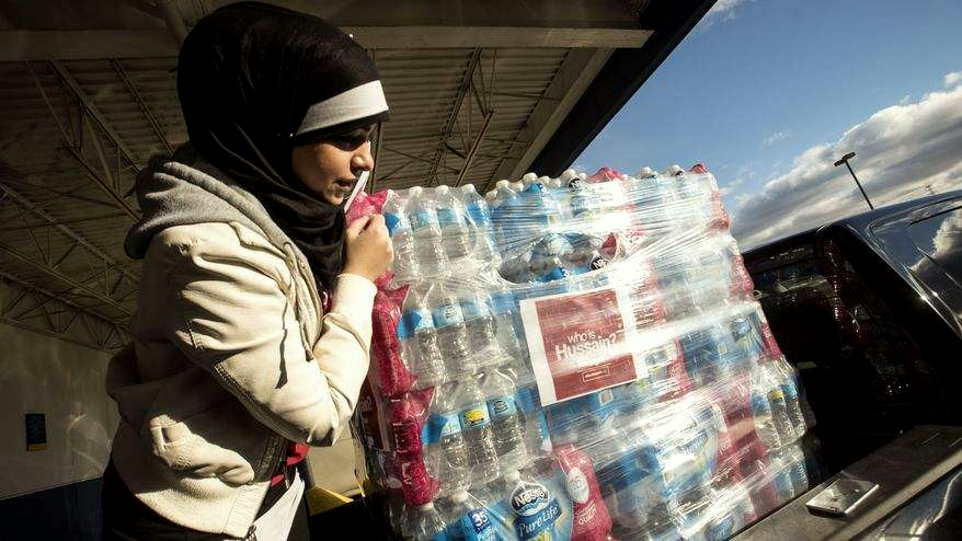 A volunteer for the Who is Hussain campaign, Balssam Fatlawi, 26, helps prepare water for donation to the Red Cross in Flint, Michigan on Sunday. (Courtesy of Mohammed Almawla)