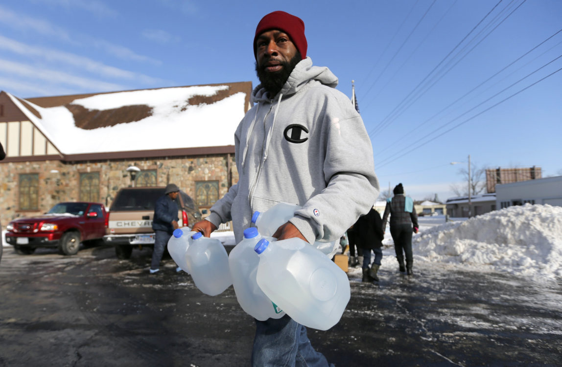 Lemott Thomas carries free water being distributed at the Lincoln Park United Methodist Church in Flint, Mich., Tuesday, Feb. 3, 2015. (AP Photo/Paul Sancya)