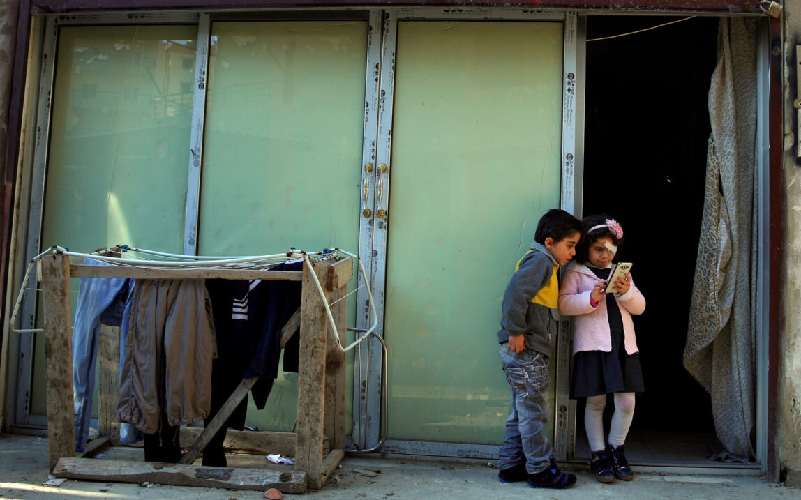 In this Tuesday, Feb. 2, 2016 photo, Syrian refugee Falak al Hourani, 7, right, and her brother Hussein Hourani, 6, who fled with their family from Homs in Syria, stand at the entrance to a shop that has been turned into a home, in the northern city of Tripoli, Lebanon. Falak, suffering from a rare form of eye cancer arrived in Italy on Thursday, the first of an estimated 1,000 refugees who are being brought here on humanitarian grounds in a pilot project aimed at dissuading people from embarking on deadly sea crossings. (AP Photo/Bilal Hussein)