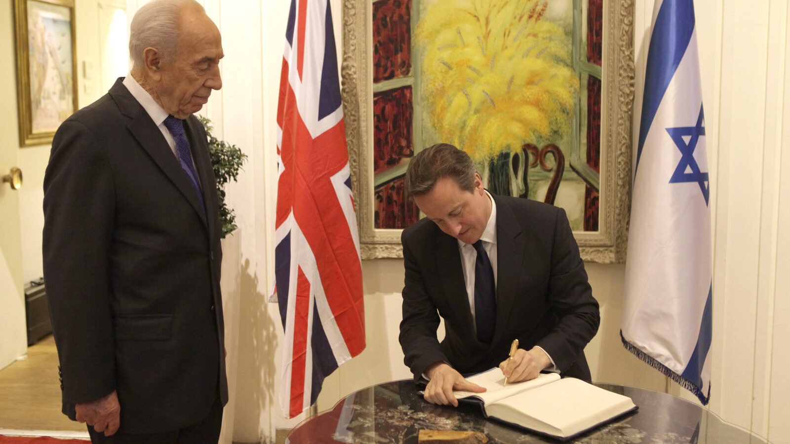 Former Israeli President Shimon Peres watches as British Prime Minister David Cameron signs a visitors book in Jerusalem Wednesday, March 12, 2014. Cameron was visiting Israel to vow support in rejecting boycott attempts against the Jewish state. (AP Photo/Dan Balilty)
