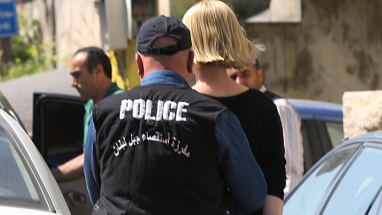 A Lebanese policeman escorts Australian TV presenter Tara Brown, who is seen handcuffed, as she is taken from a Lebanese courthouse where she was questioned by an investigative judge over suspicion of taking part in an abduction attempt of two Lebanese-Australian children, in Baabda, east of Beirut, Lebanon, Monday April, 18, 2016. (AP Photo/Hussein Malla)