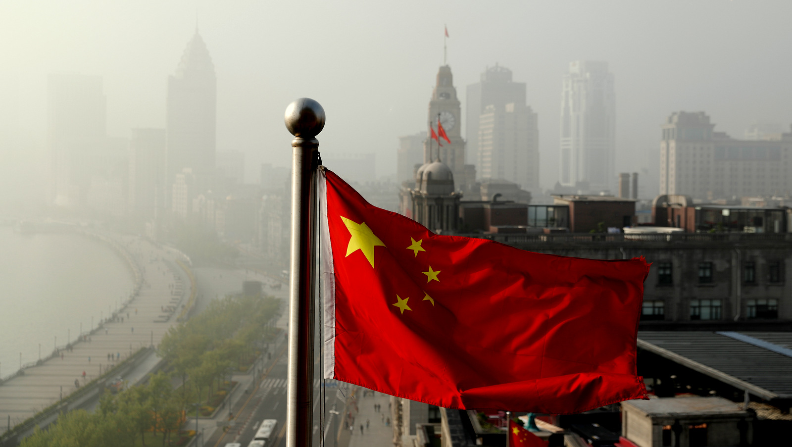 A Chinese national flag flutters against the office buildings at the Shanghai Bund shrouded by pollution and fog in Shanghai, China, Thursday, April 14, 2016. World finance officials who meet in Washington this week confront a bleak picture: Eight years after the financial crisis erupted, the global economy remains fragile and at risk of another recession. (AP Photo/Andy Wong)