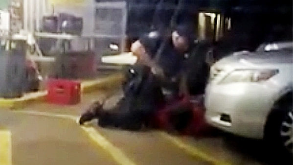 In this Tuesday, July 5, 2016 photo made from video, Alton Sterling is held by two Baton Rouge police officers, with one holding a hand gun, outside a convenience store in Baton Rouge, La. Moments later, one of the officers shot and killed Sterling, a black man who had been selling CDs outside the store, while he was on the ground.