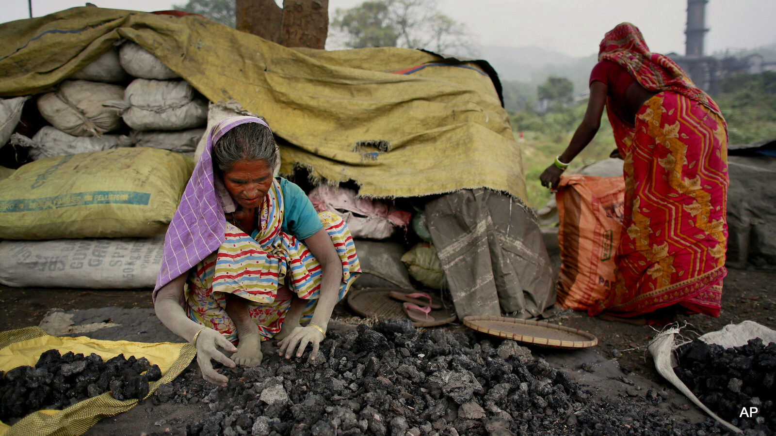 Indian women use bare hands to pick reusable pieces from heaps of used coal discarded by a carbon factory in Gauhati, India, Monday, Dec. 14, 2015.