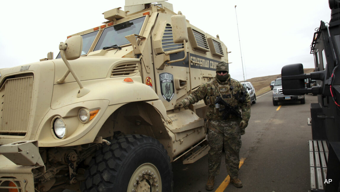 A member of the Stutsman County SWAT team who declined to give his name nor to be identifiable by badge stands guard by an armored personnel carrier while deployed to watch protesters demonstrating against the Dakota Access Pipeline near the Stand Rock Sioux Reservation, in Cannon Ball, N.D., Sunday, Oct. 30, 2016.
