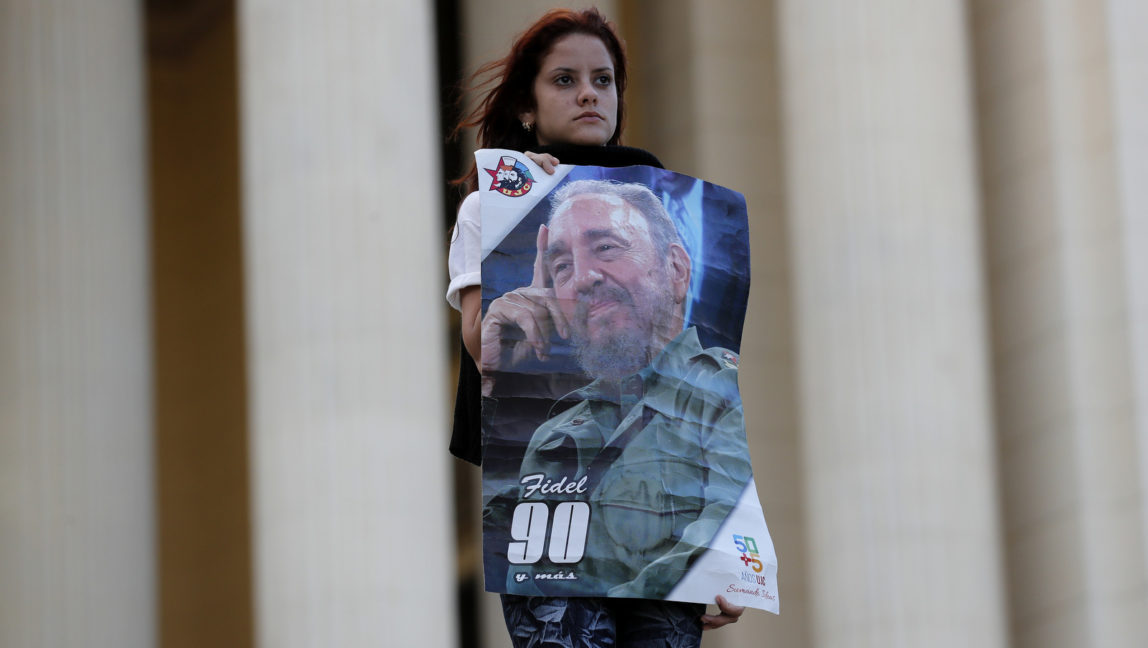 A student stands at attention holding images of Fidel Castro at the university where Castro studied law as a young man, during a vigil in Havana, Cuba, Sunday, Nov. 27, 2016. Castro, who led a rebel army to improbable victory in Cuba, embraced Soviet-style communism and defied the power of U.S. presidents during his half century rule, died Friday at age 90. (AP Photo/ Dario Lopez-Mills)