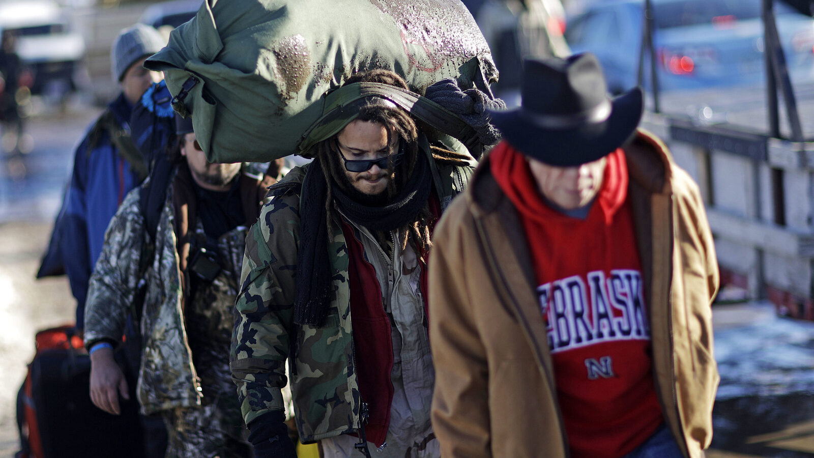 Marine Corps veteran Nesky Hernandez, center, carries his pack after arriving with fellow veterans at the Oceti Sakowin camp where people have gathered to protest the Dakota Access oil pipeline in Cannon Ball, N.D., Sunday, Dec. 4, 2016. Tribal elders have asked the military veterans joining the large Dakota Access pipeline protest encampment not to have confrontations with law enforcement officials, an organizer with Veterans Stand for Standing Rock said Sunday, adding the group is there to help out those who've dug in against the four-state, $3.8 billion project. (AP Photo/David Goldman)