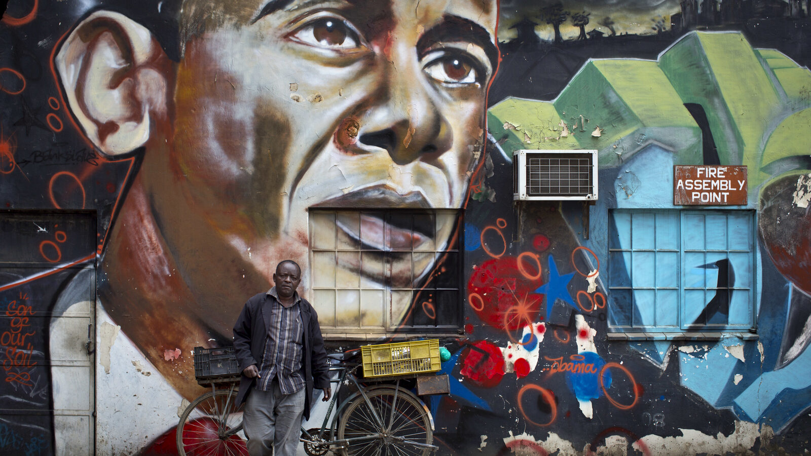 A man walks away after leaning his bicycle against a mural of President Barack Obama at the GoDown Arts Centre in Nairobi, Kenya ahead of the visit of Obama. (AP/Ben Curtis)