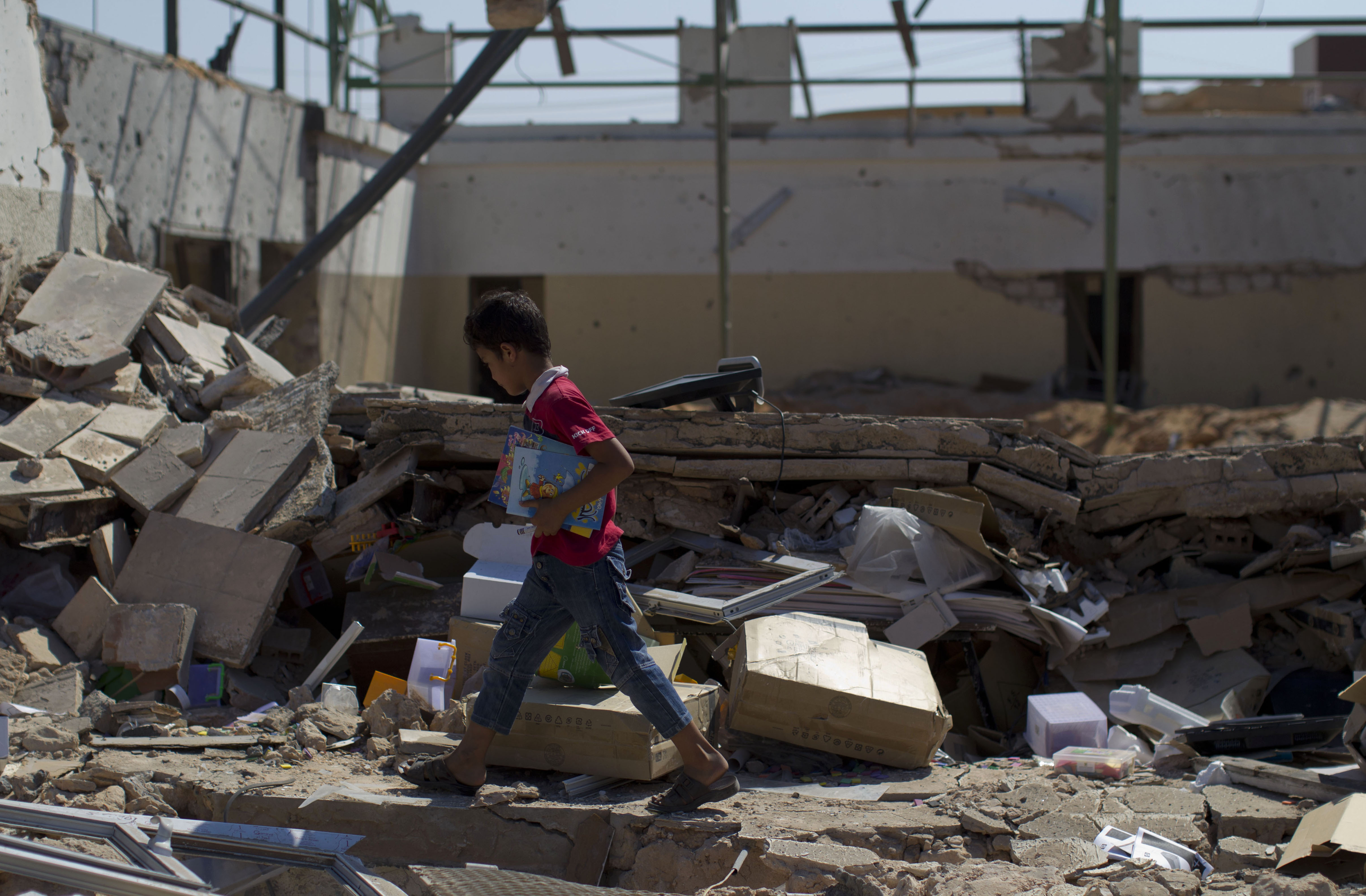 A boy looks for items among the debris inside a bomb damaged school in Tripoli, Libya, Aug. 19, 2011. (AP/Dario Lopez-Mills)