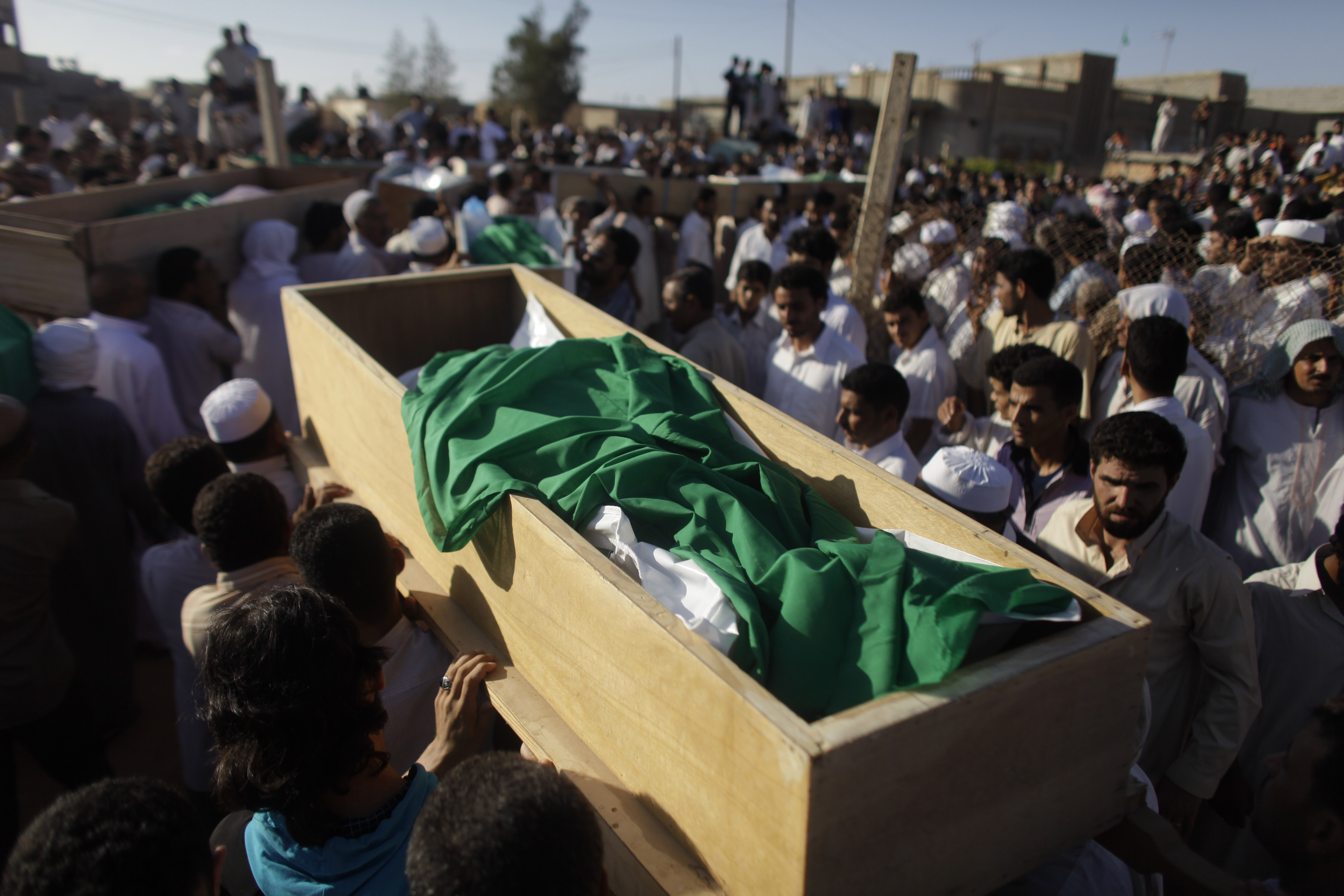 Men carry coffins during the burial of more than two dozen people after an alleged NATO bombing in the town of Majar, near in Zlitan, Libya, Aug. 9, 2011. Several homes were hit and reportedly 28 people, some of them women and children, were later buried. (AP/Dario Lopez-Mills)