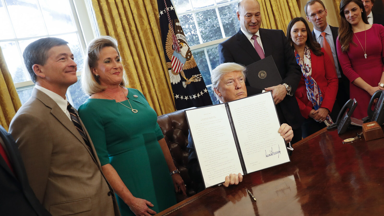 President Donald Trump holds up an executive order after his signing the order in the Oval Office of the White House in Washington, Friday, Feb. 3, 2017. The executive order that will direct the Treasury secretary to review the 2010 Dodd-Frank financial oversight law, which reshaped financial regulation after 2008-2009 crisis. On the far left are Rep. Jeb Hensarling, R-Texas, and Rep. Ann Wagner, R Mo. (AP/Pablo Martinez Monsivais)