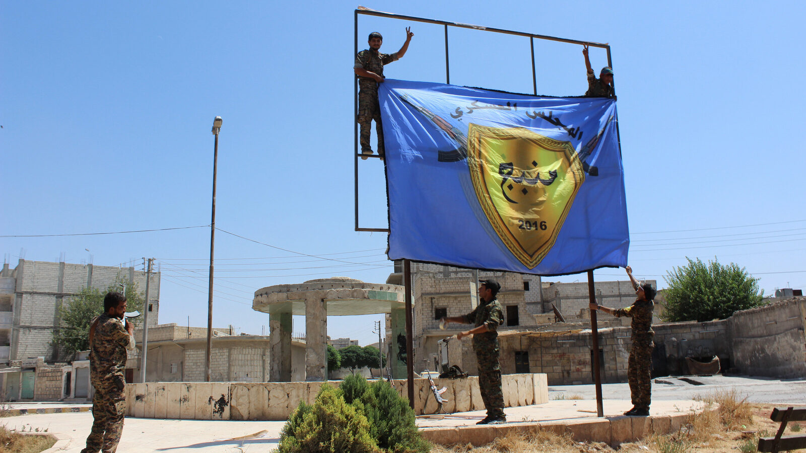 U.S.-backed, Kurdish-led Syria Democratic Forces raise their flag in the center of the town of Manbij after driving ISIS out of the area, in Aleppo province, Syria. (ANHA via AP)