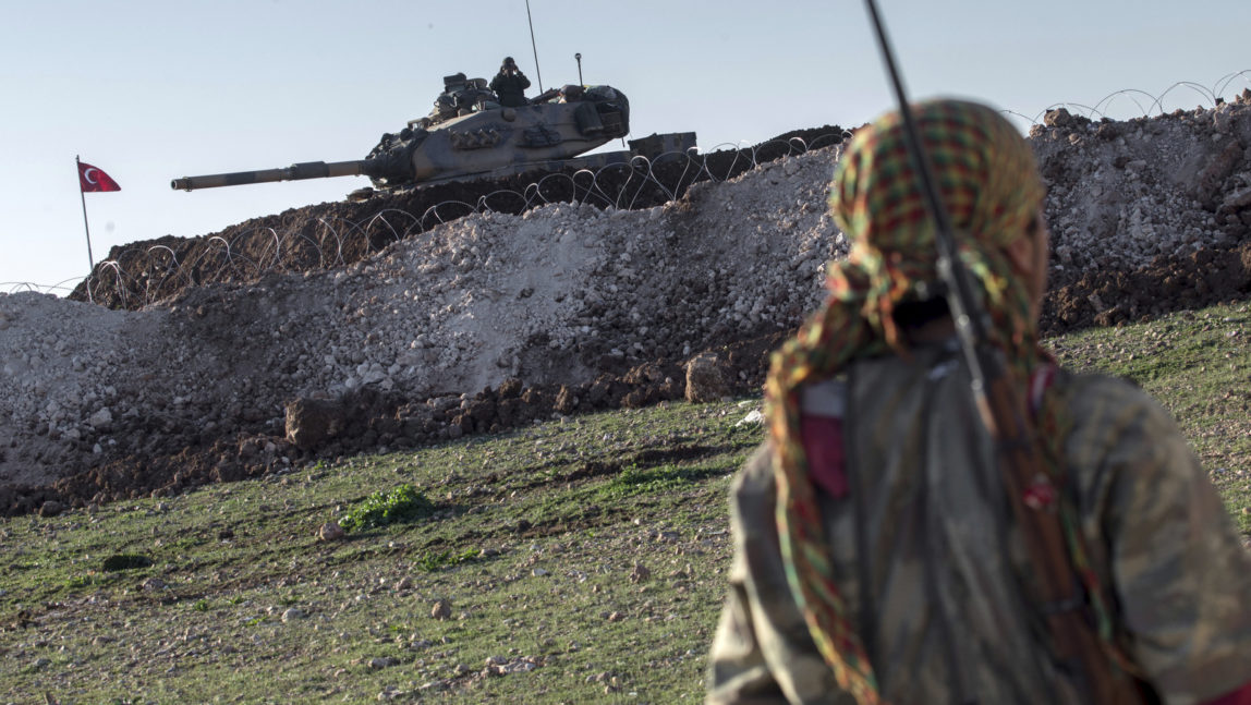 Syrian Kurdish militia member of the YPG patrols near a Turkish army tank in Esme village in Aleppo province, Syria. (AP/Mursel Coban)