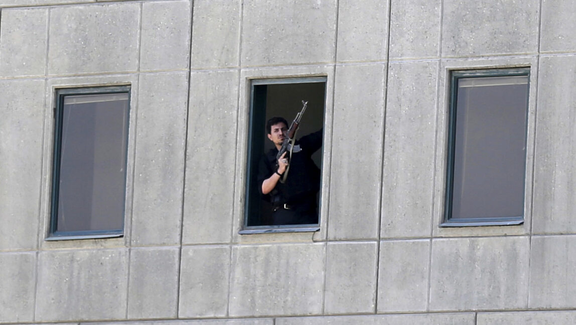 An armed man stands in a window of the parliament building in Tehran, Iran, Wednesday, June 7, 2017. . (Fars News/Omid Vahabzadeh via AP)