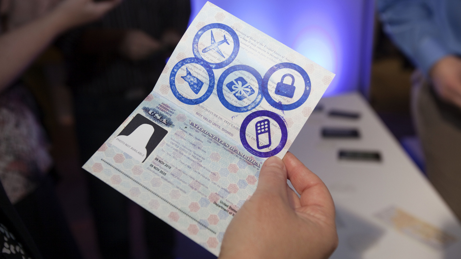 Claudia Lombana, PayPal's shopping specialist, stamps a guest's passport as he visits the travel section of PayPal's Cashless Utopia in New York (Victoria Will/AP)