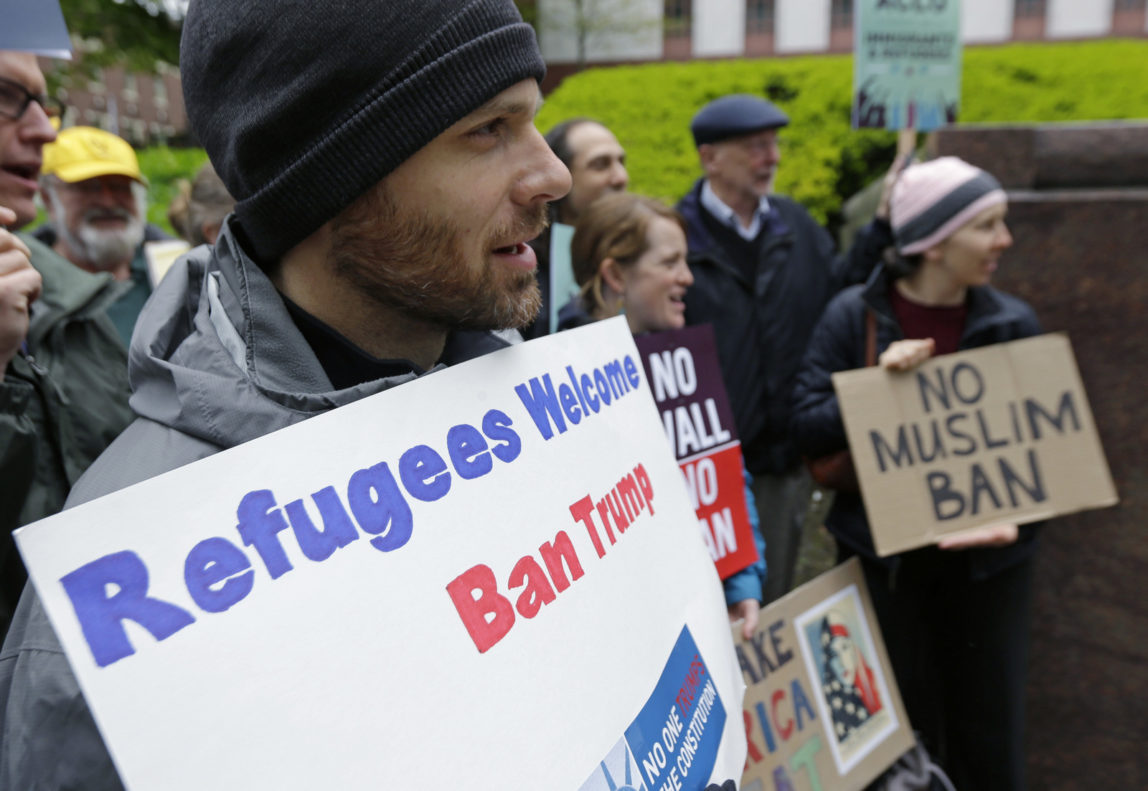 Miles Treakle, left, of Seattle, holds a sign that reads "Refugees Welcome Ban Trump," as he protests against President Donald Trump's revised travel ban, May 15, 2017, outside a federal courthouse in Seattle. (AP/Ted S. Warren)