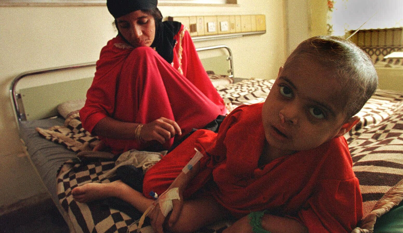 Suffering from leukemia, 5 year-old Sahira lies in her bed as her mother weeps at the Saddam Children's Hospital in Baghdad Tuesday, Jan. 12, 1999. (AP/Murad Sezer)