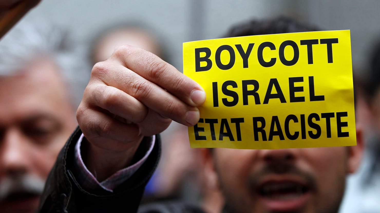 A demonstrator displays a sign reading "Boycott Israel, racist state". (Photo: Reuters)