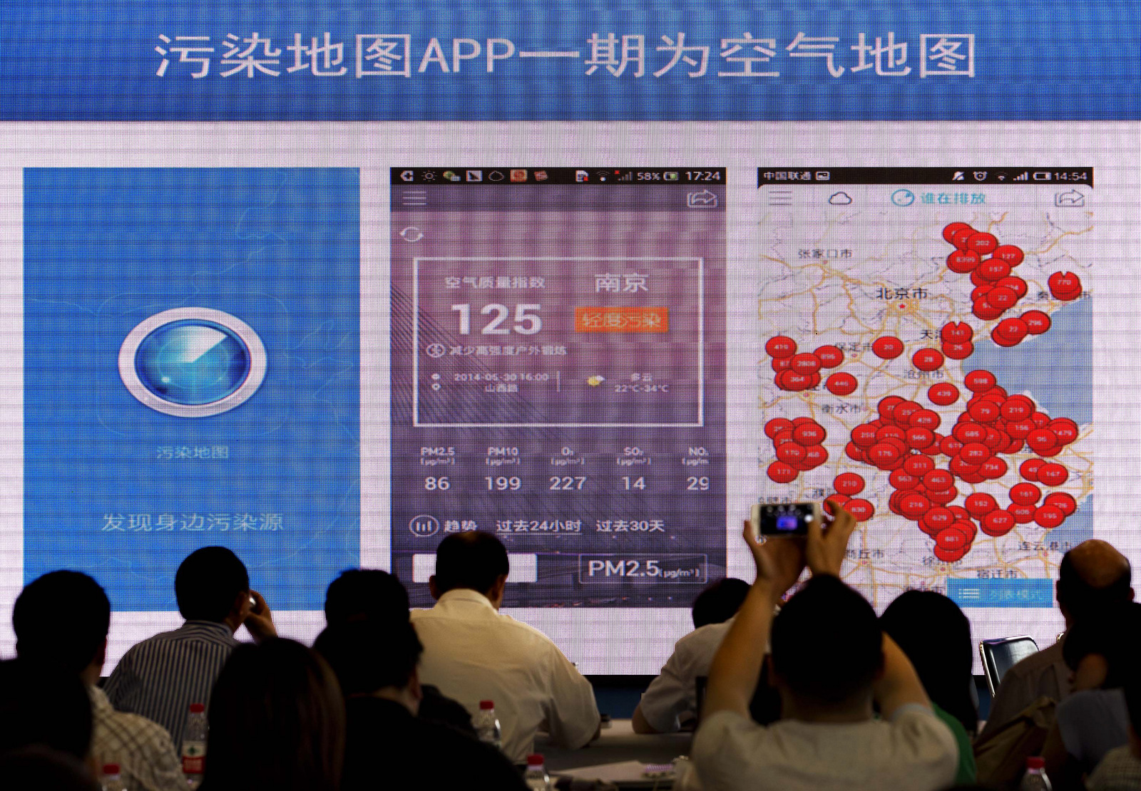 A journalist uses his smartphone to take a photo of a projector screen showing a real-time air quality app, which has bee introduced by Ma Jun, director of Institute of Public and Environmental Affairs after its official launching at the Environmental Protection Bureau in Beijing, China, June 9, 2014. (AP/Andy Wong)