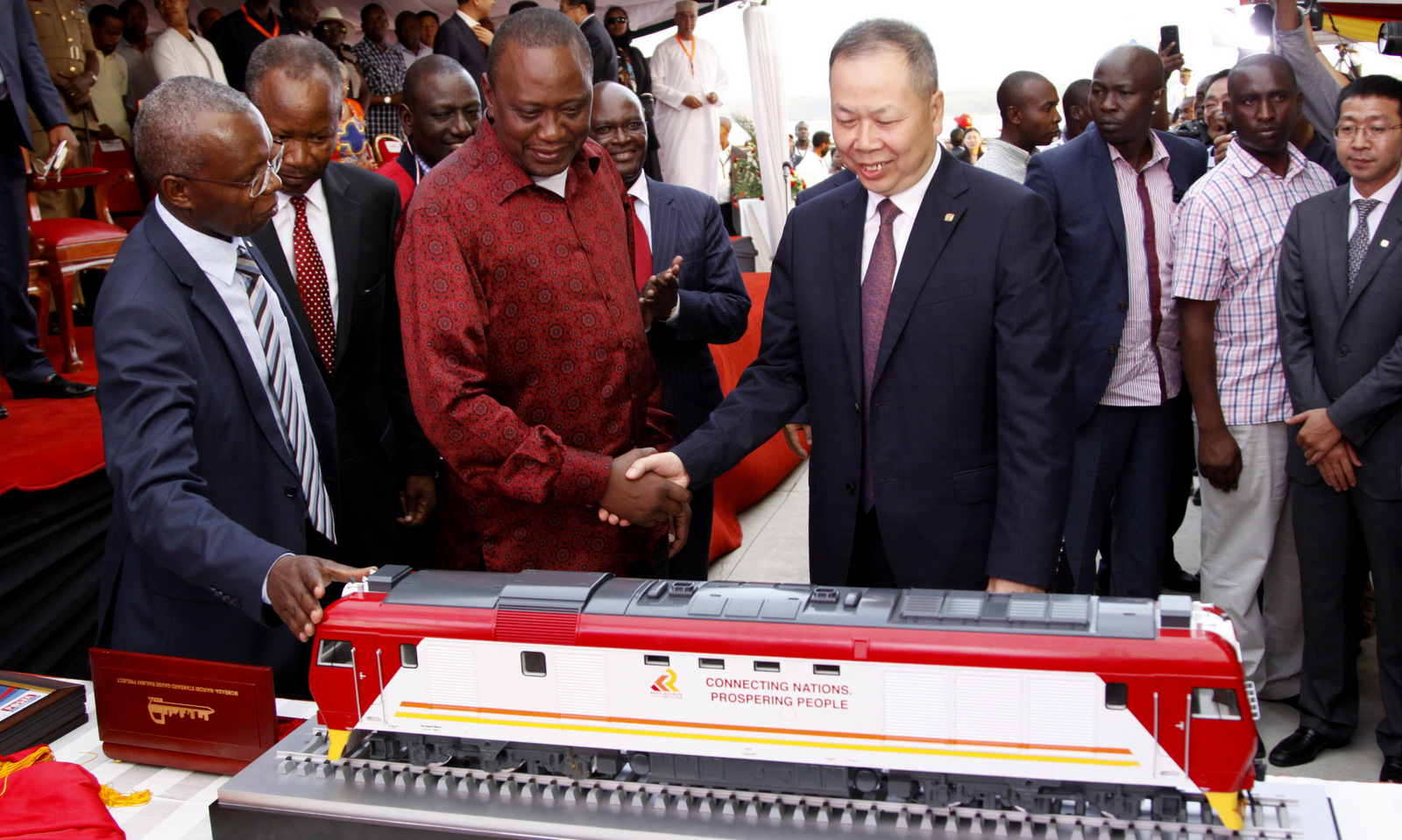 Kenyan President Uhuru Kenyatta 2nd left, and Chen Fenjian president of CCC shaking hands next to a model of a locomotive in Mombasa, Kenya, May 30, 2017. The president opened the country's largest infrastructure project since independence, a Chinese-backed railway costing nearly $3.3 billion that eventually will link a large part of East Africa to a major port on the Indian Ocean. (AP/Khalil Senosi)