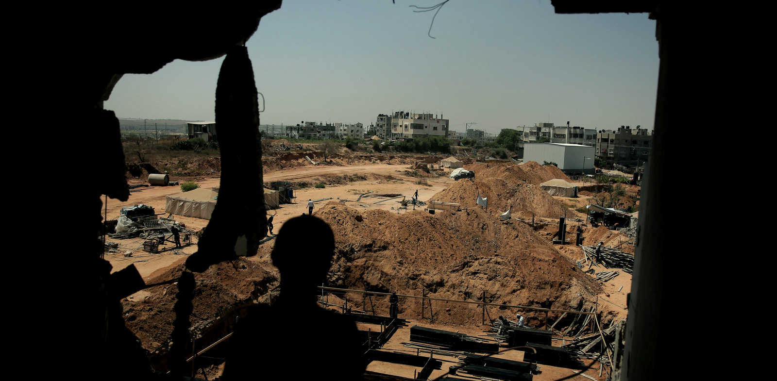 A Palestinian boy looks from his family's destroyed house as workers rebuild another home destroyed by Israel's aerial bombardment of the Shijaiyah neighborhood in eastern Gaza City, July 23, 2015. (AP/Khalil Hamra)