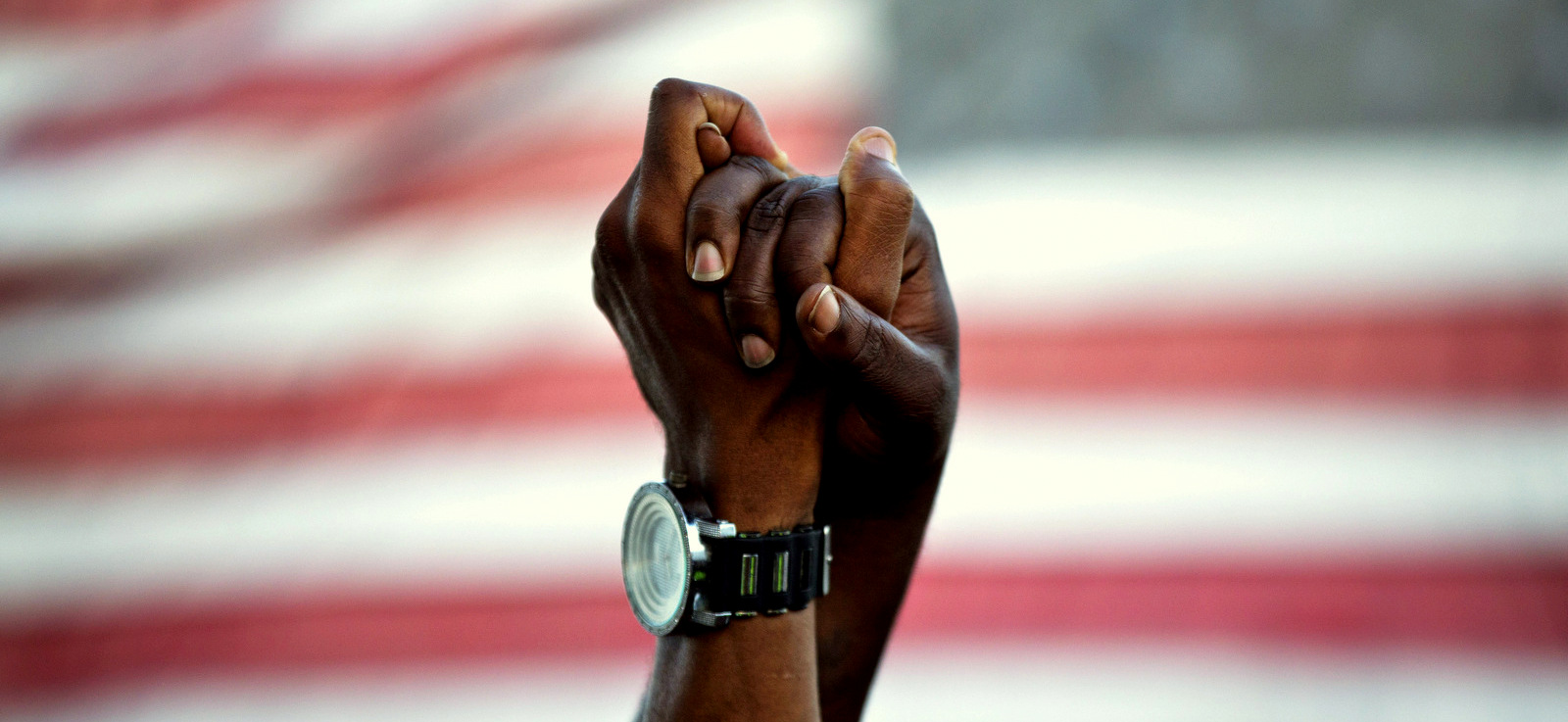 People join hands against the backdrop of an American flag as thousands of marchers meet in the middle of Charleston's main bridge in a show of unity after nine black church parishioners were gunned down during a Bible study, Sunday, June 21, 2015, in Charleston, S.C. (AP Photo/David Goldman)