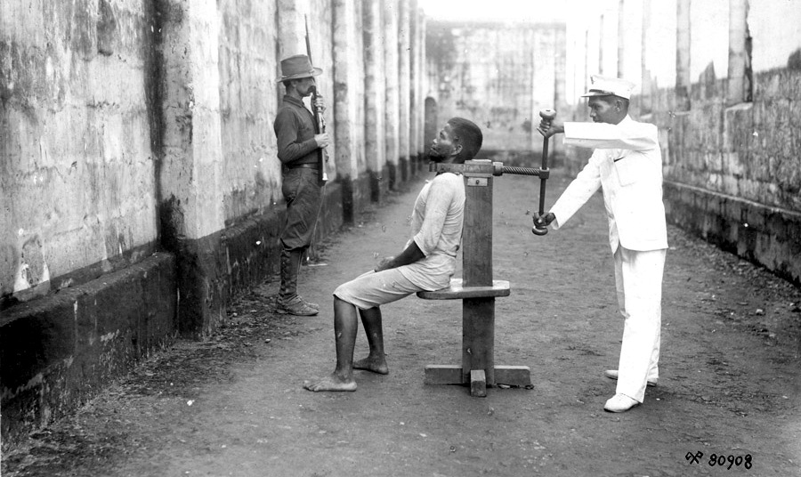 A Filipino insurrectionist is executed, one of 31 killed in Manila, Philippines on that day in 1900, with a garroting machine. An American soldier stands guard in the background. (Photo: National Archives of the Philippines)