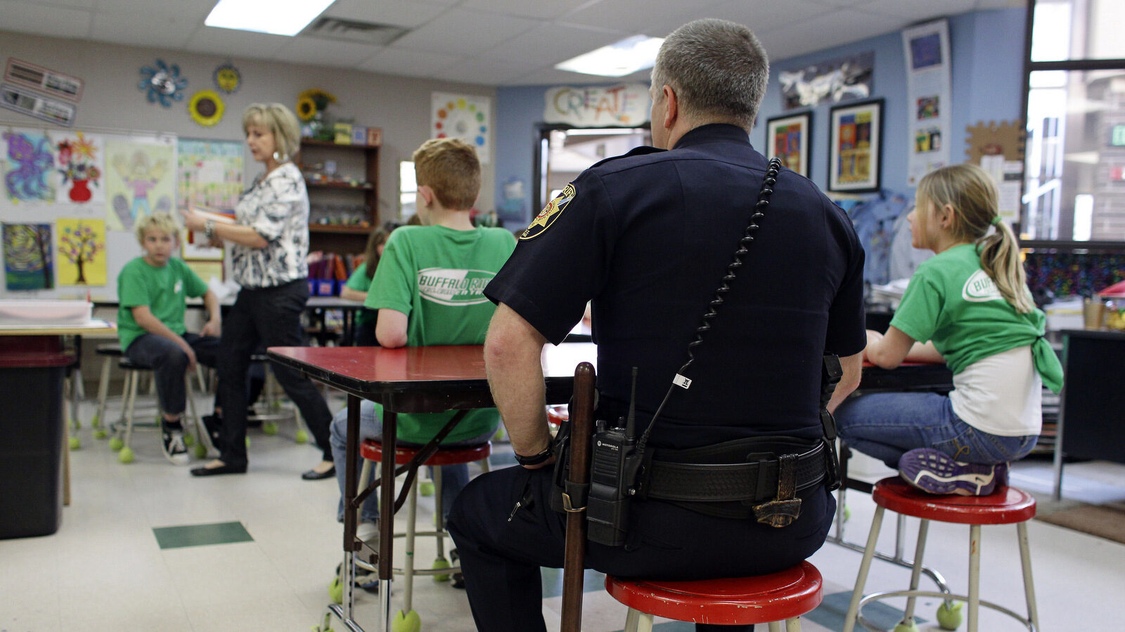 A Douglas County Sheriff sits in on part of an art class at Buffalo Ridge Elementary School, part of a new cooperative effort between law enforcement and schools for more routine police presence at local elementary schools, in Castle Pines, Colo. (AP/Brennan Linsley)