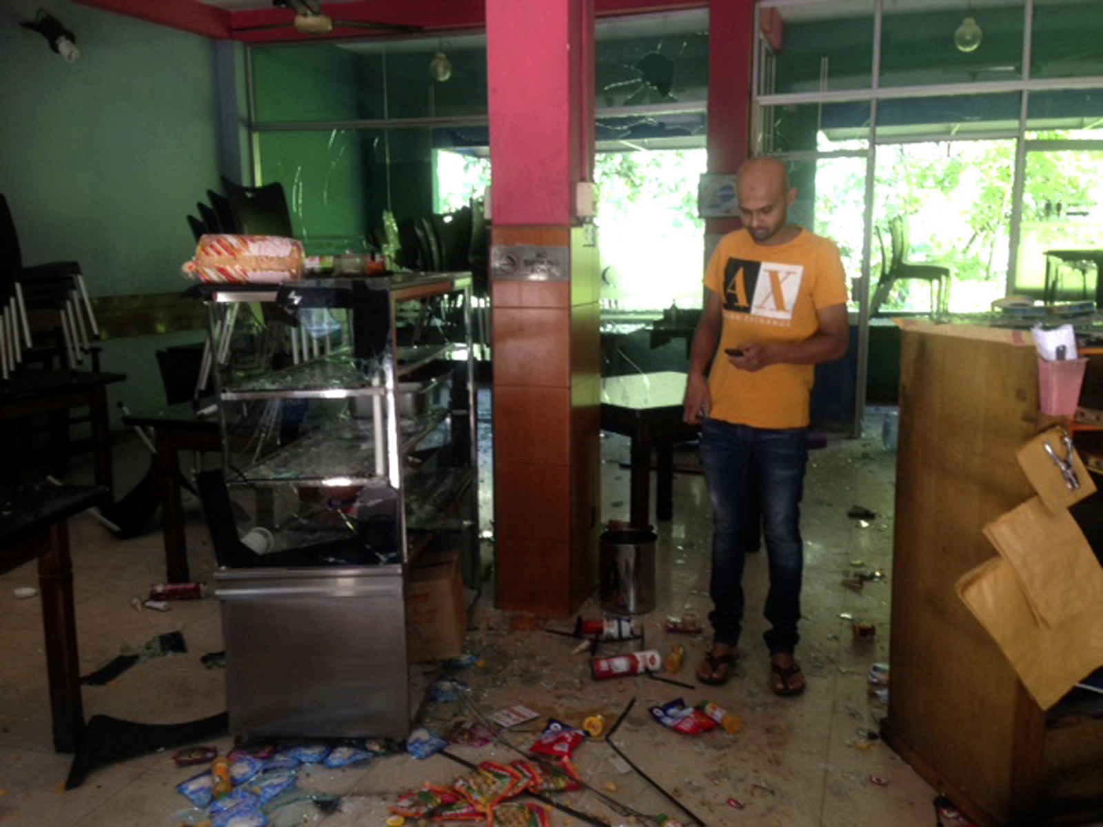 Mohamed Ramzeen makes a call from his mobile phone standing in his vandalized small restaurant in Pilimathalawa, Sri Lanka, March 8, 2018. About 50 people broke into Ramzeen's small restaurant destroying nearly everything they found, he said. Buddhist mobs swept through Muslim neighborhoods in Sri Lanka's central hills, destroying stores and restaurants despite a curfew, a state of emergency and a heavy deployment of security forces. (AP/Bharatha Mallawarachchi)